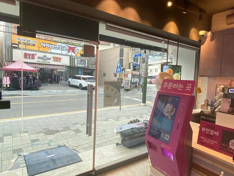 매장 안쪽에서 본 무인 주문 키오스크와 통유리 창